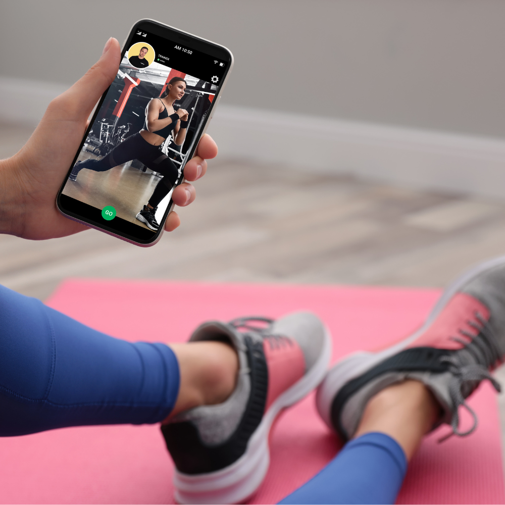 Eine Person hält ein Handy in der Hand, während sie auf einer Sportmatte sitzt.